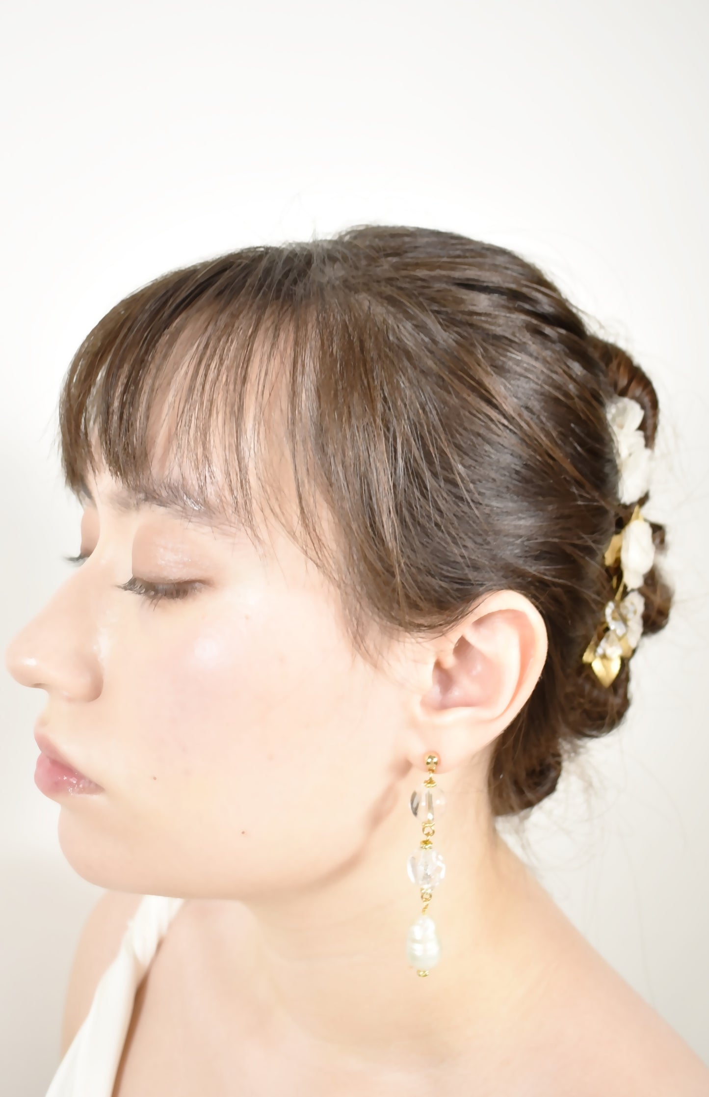 Woman with styled hair and pearl earrings against a white background