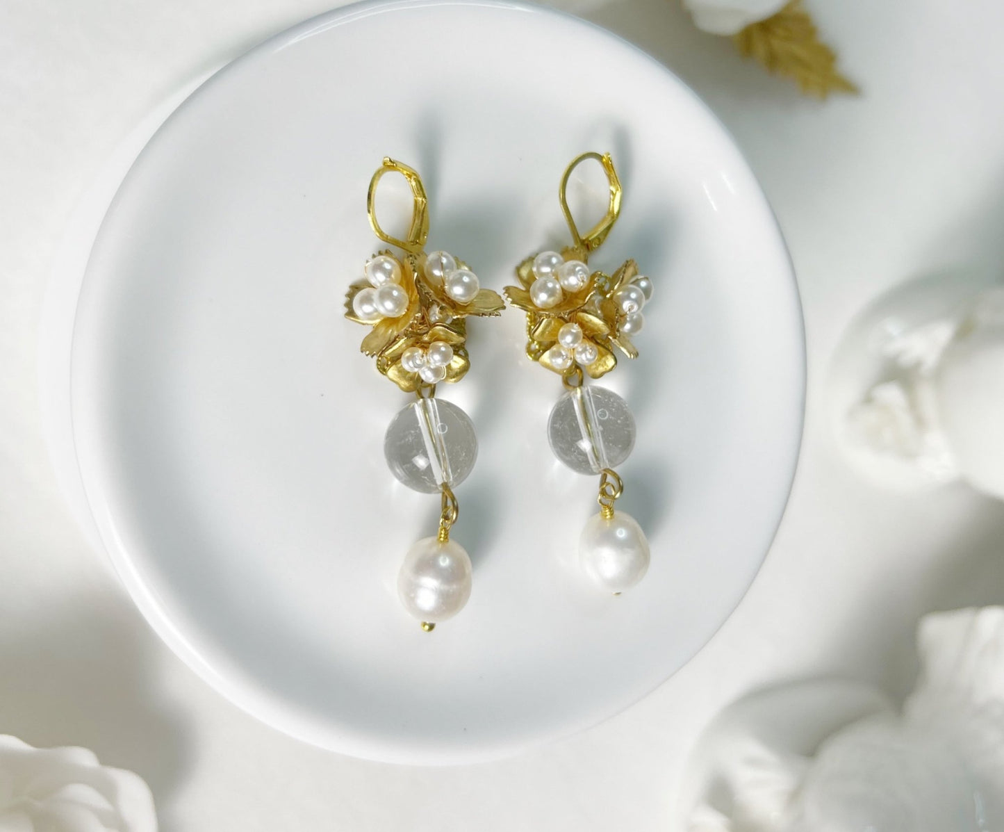 Pair of gold and pearl earrings on a white dish
