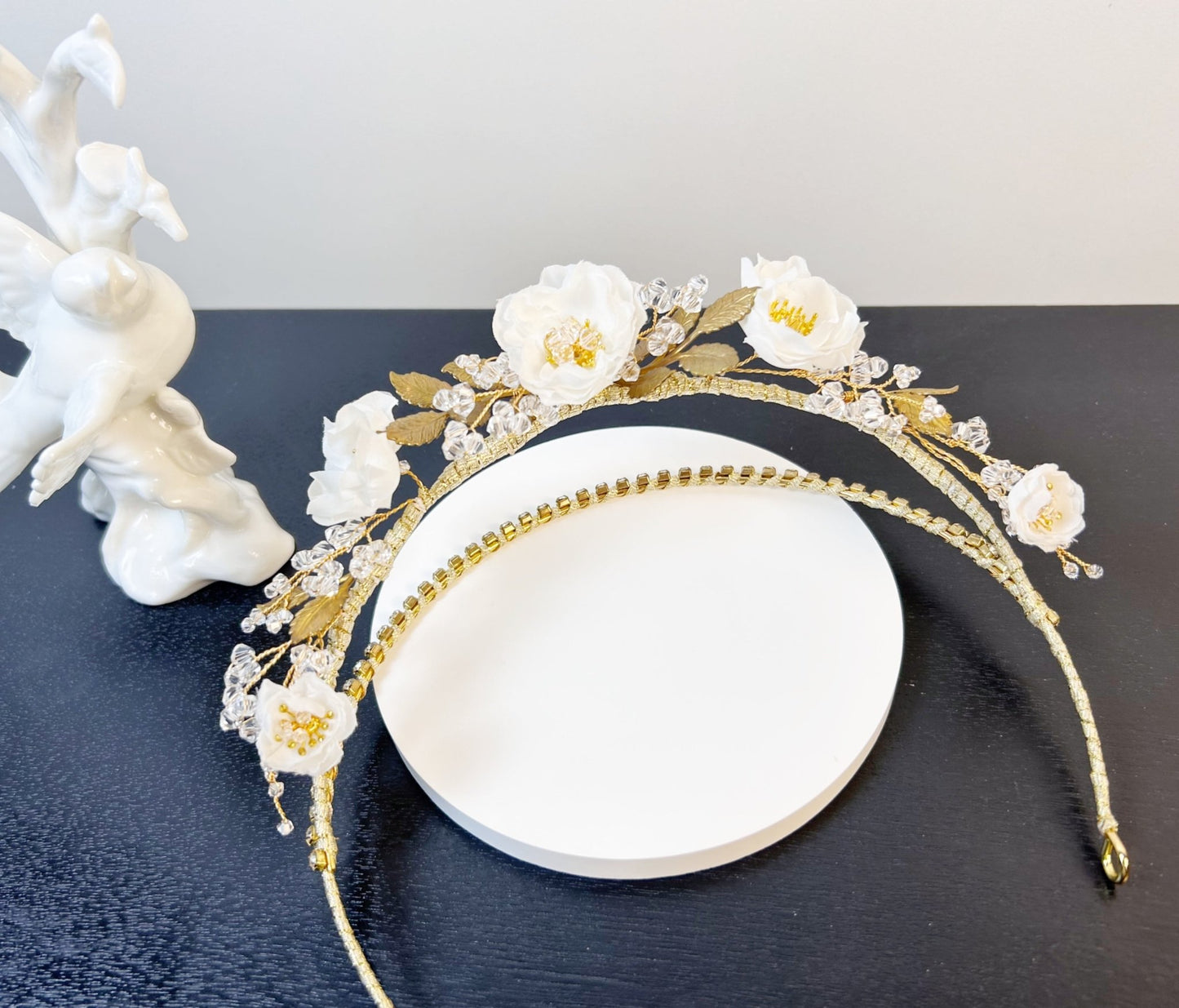 Gold headband with white flowers on a black surface