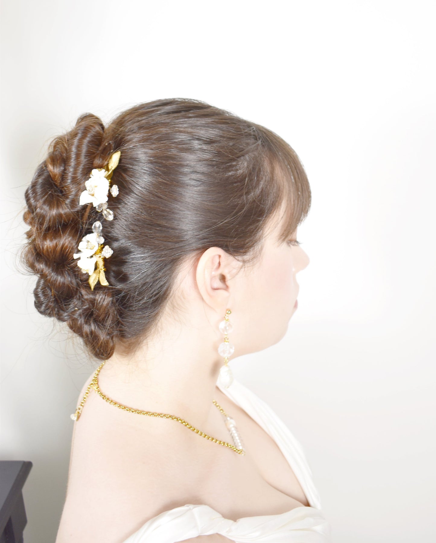 Woman with elegant hair styled with floral hairpins against a white background
