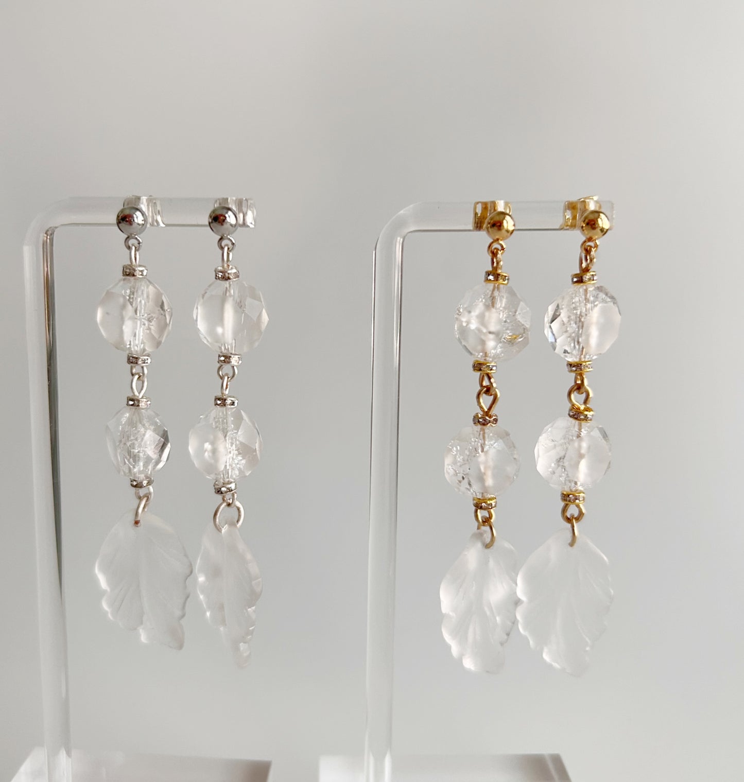Pair of crystal drop earrings on clear stands against a white background