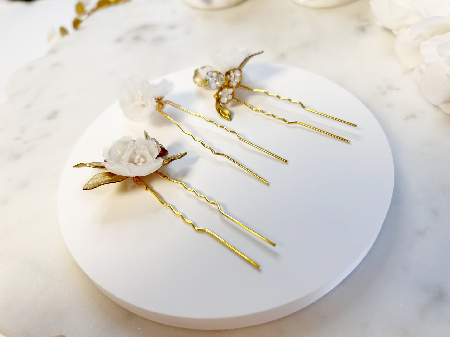 Gold hairpins with floral and pearl details on marble