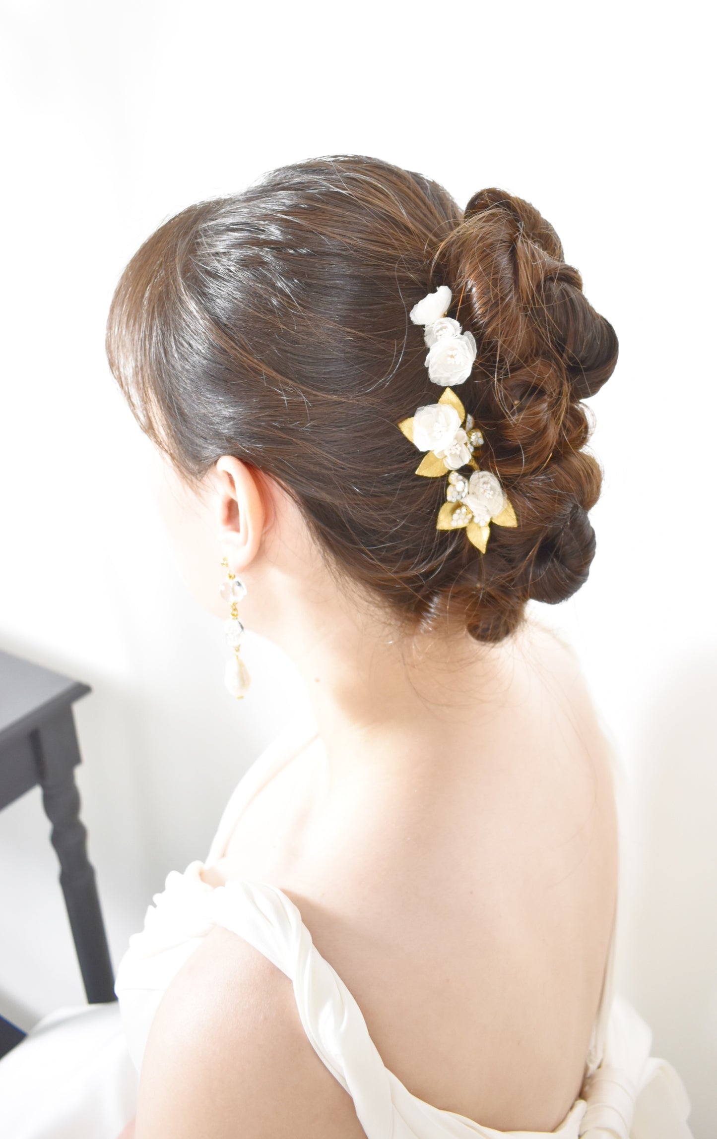 Woman with elegant hair styled in an updo with floral accessories on a white background