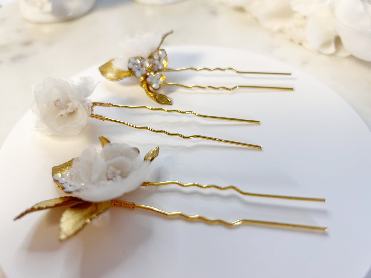 Decorative hair pins with floral designs on a white surface