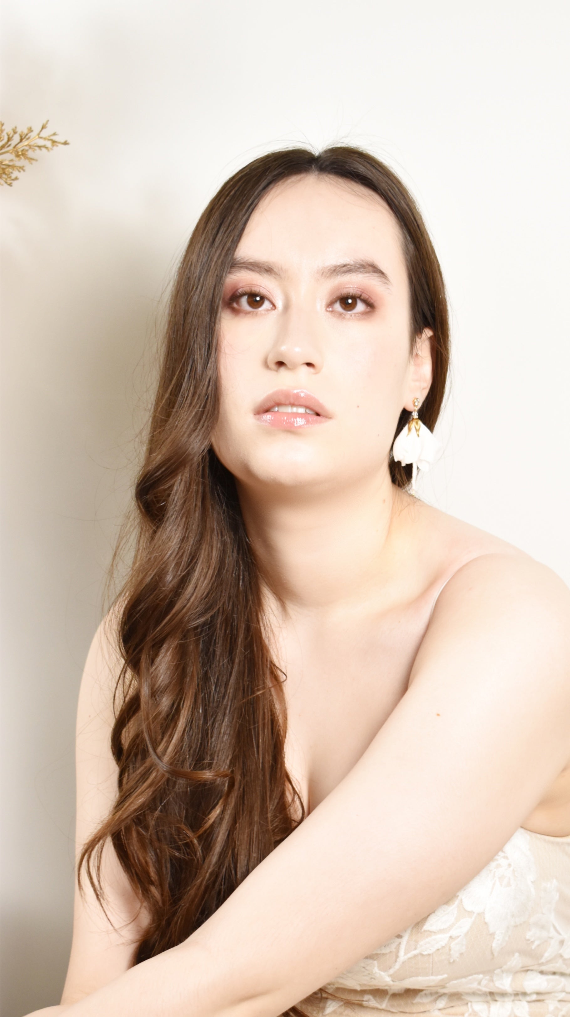 Woman with long hair wearing silk wedding earrings against a neutral background