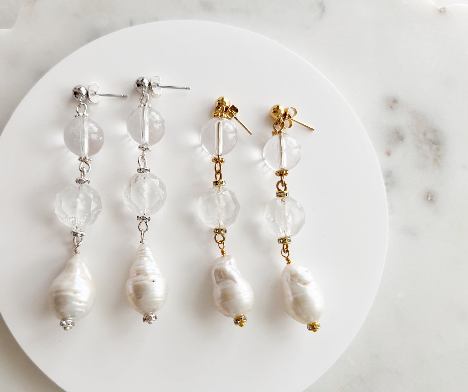 Pair of pearl earrings on a white plate with a marble background
