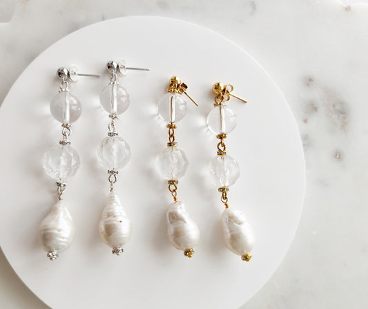Pair of pearl earrings on a white plate with a marble background