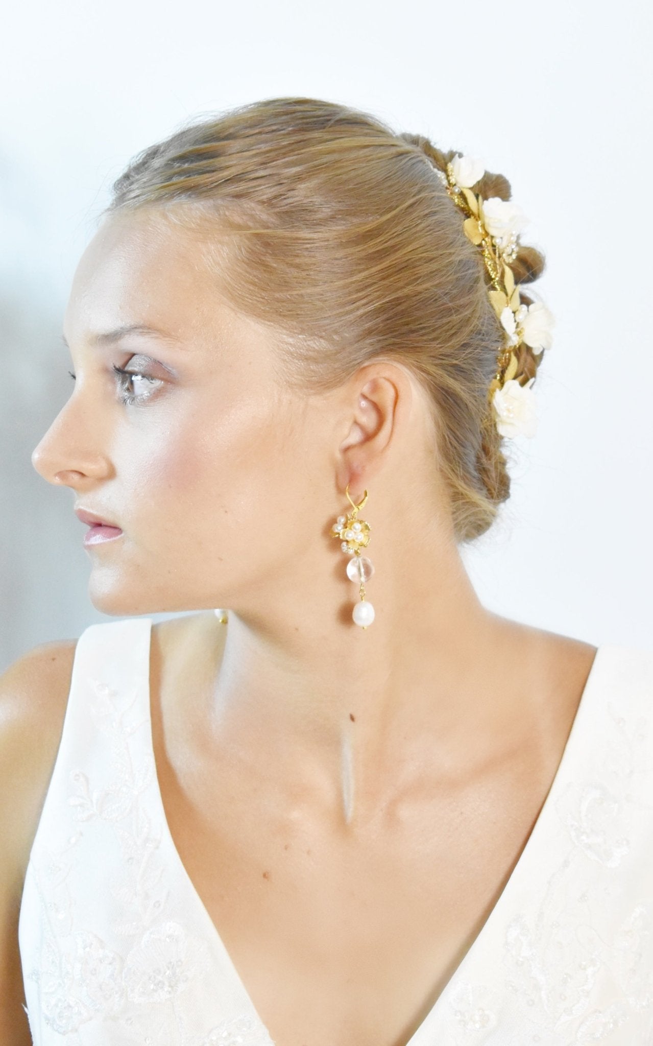 Woman wearing gold earrings with pearls against a white background
