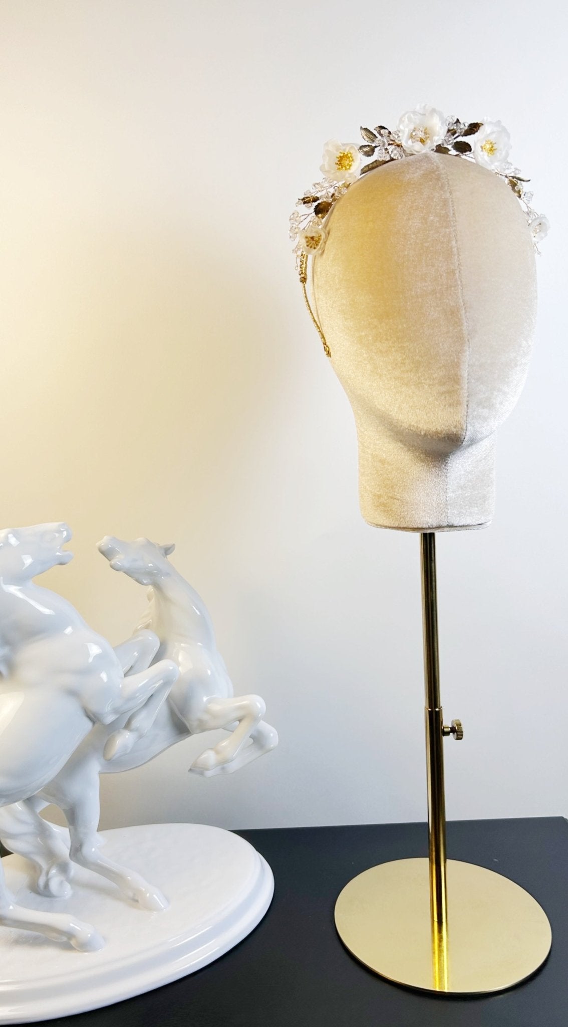 Mannequin head with floral crown on a stand against a white background