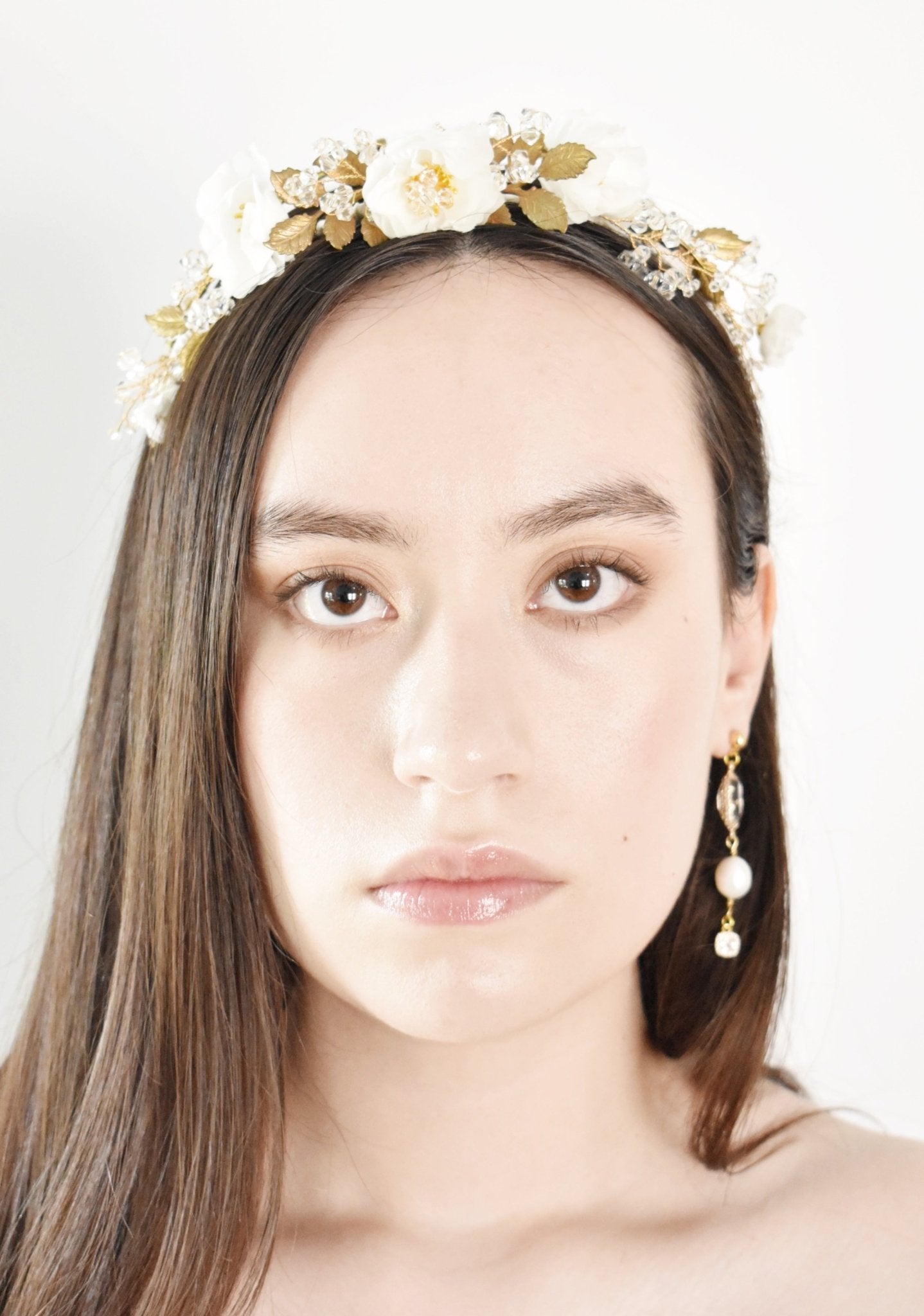 Woman wearing a decorative headpiece with flowers and gold accents on a white background