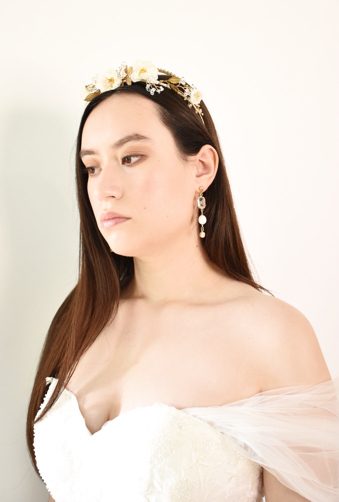 Woman wearing a decorative headpiece and earrings against a plain background