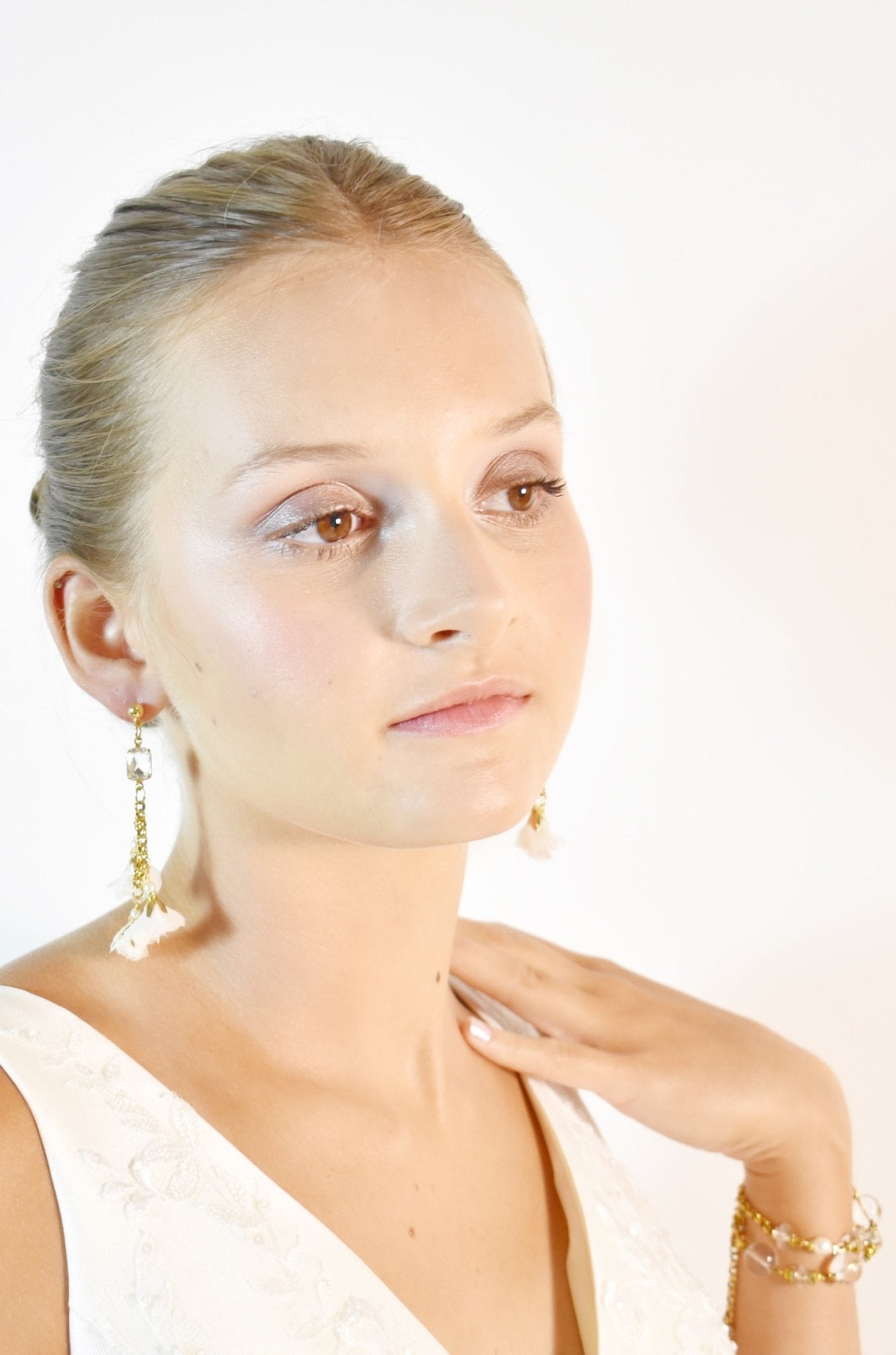 Woman wearing gold earrings and a bracelet on a white background