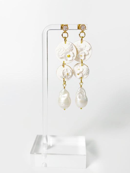 Pearl earrings on a clear stand against a white background