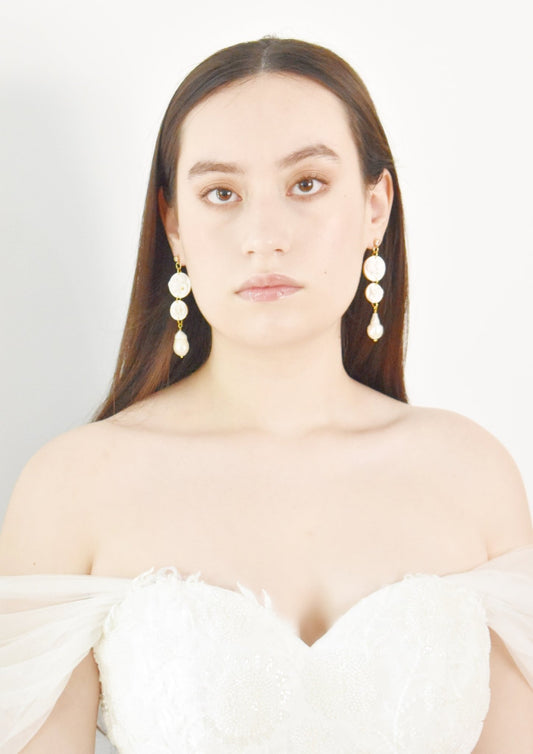 Woman wearing large, round earrings against a plain background