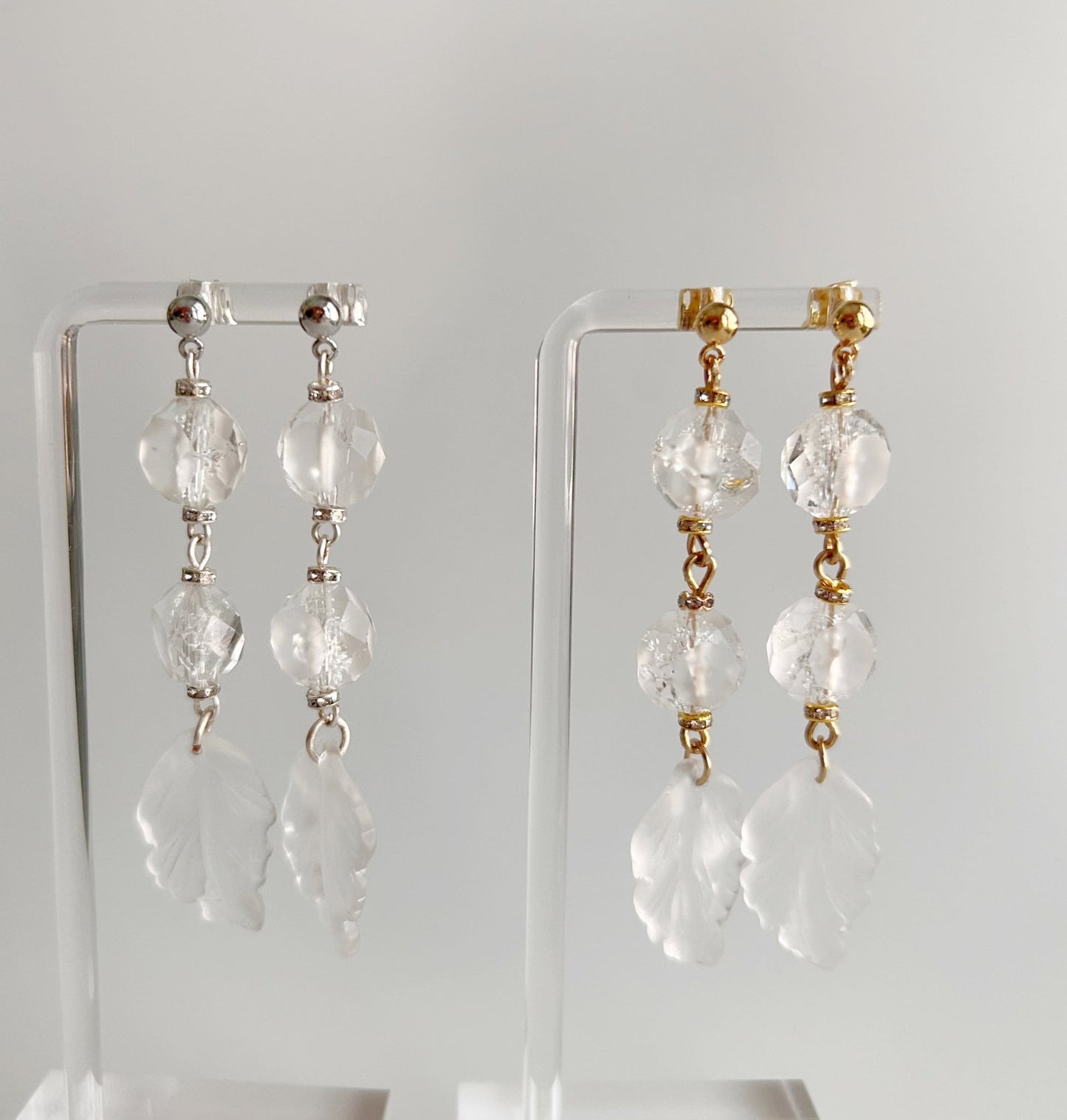 Pair of crystal drop earrings on clear stands against a white background