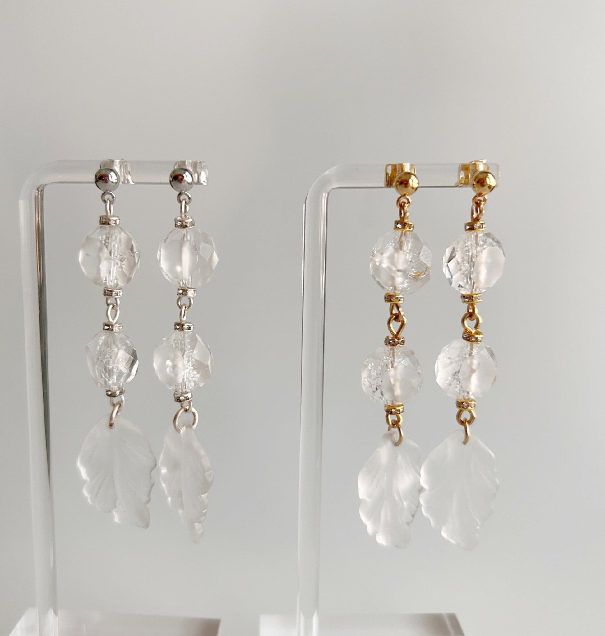 Pair of crystal drop earrings on clear stands against a white background
