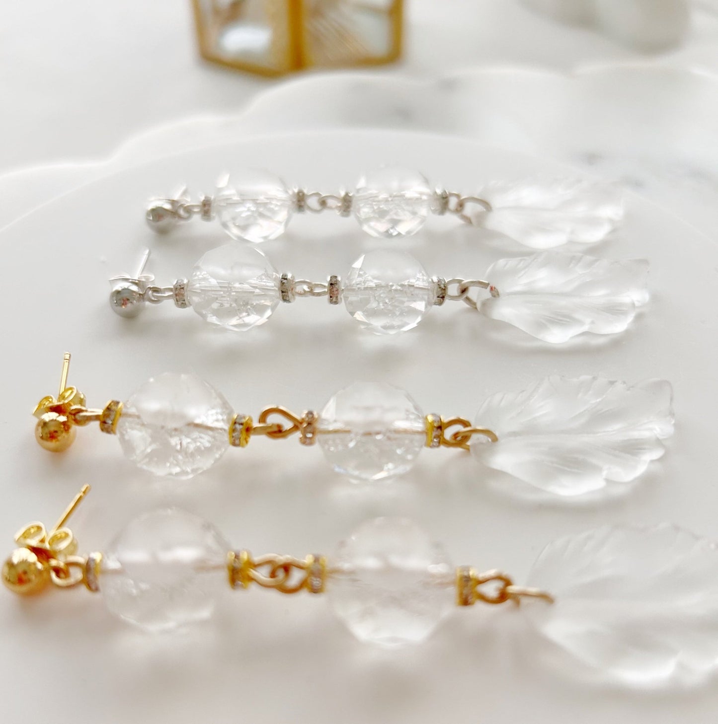 Clear beaded earrings with gold hooks on a white surface