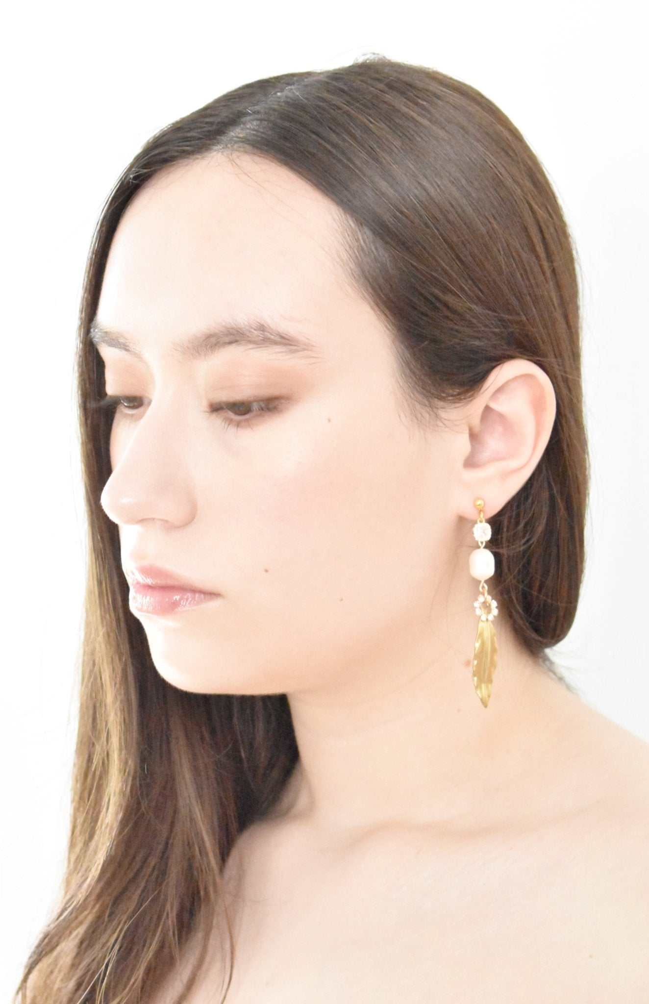 Woman wearing pearl and gold earrings on a white background