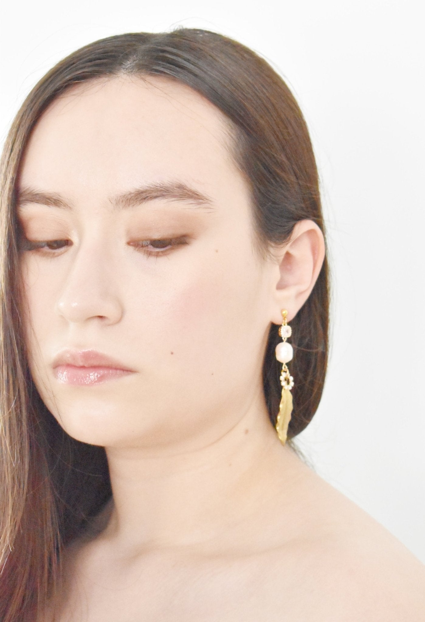 Close-up of a person wearing gold earrings with a plain background