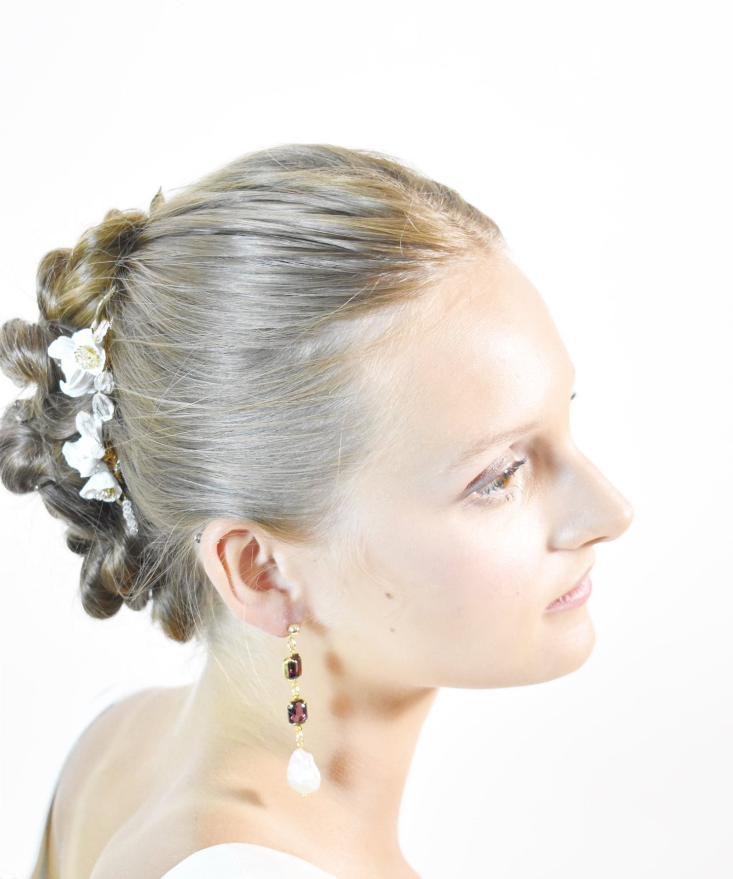 Woman with styled hair and limited edition earrings on a white background