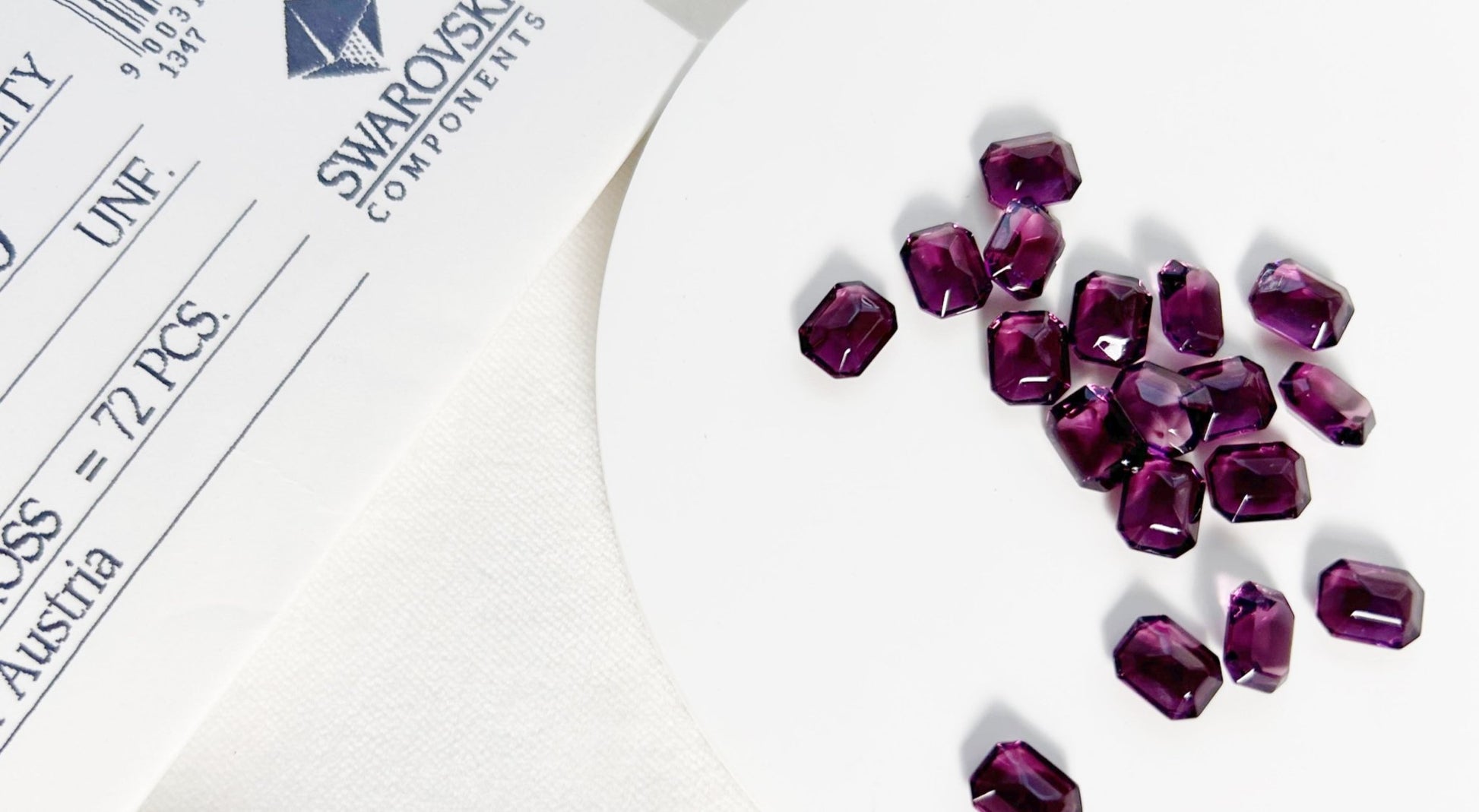 Purple gemstones on a white surface with Swarovski Components branding in the background.