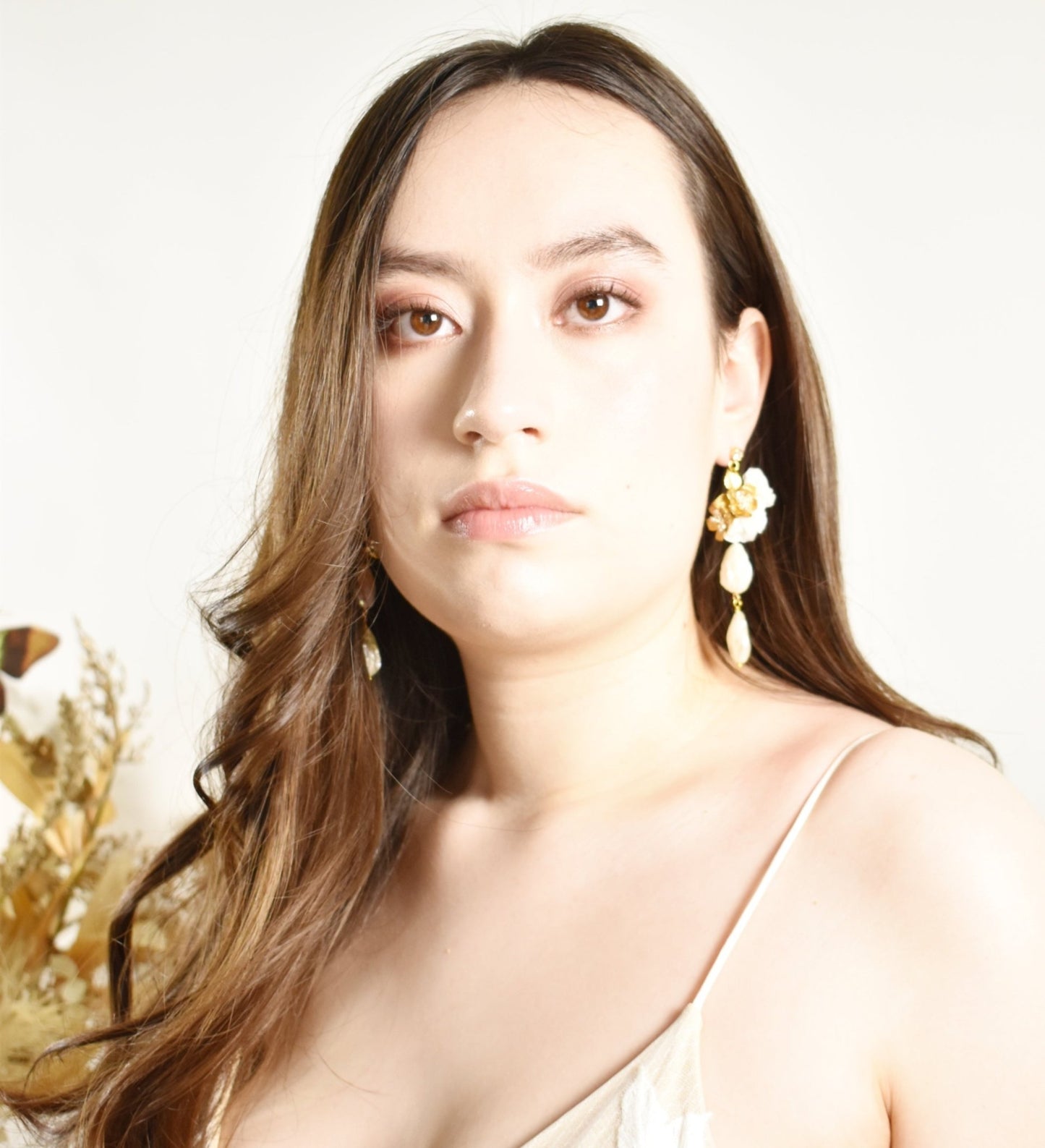 Woman wearing gold earrings with a neutral background