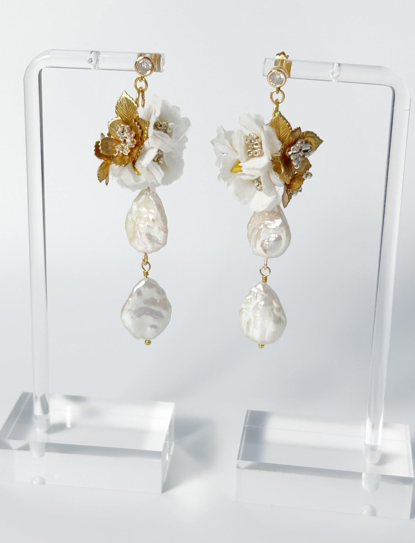 Pearl and floral earrings on a clear stand