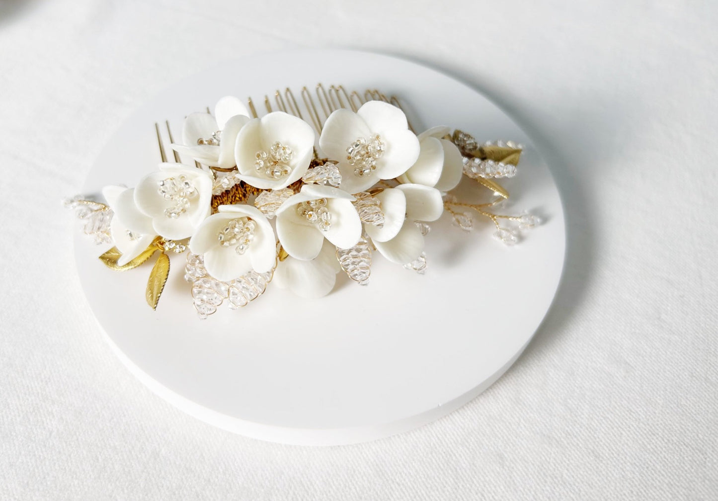 Floral hair comb with white flowers and gold accents on a white background