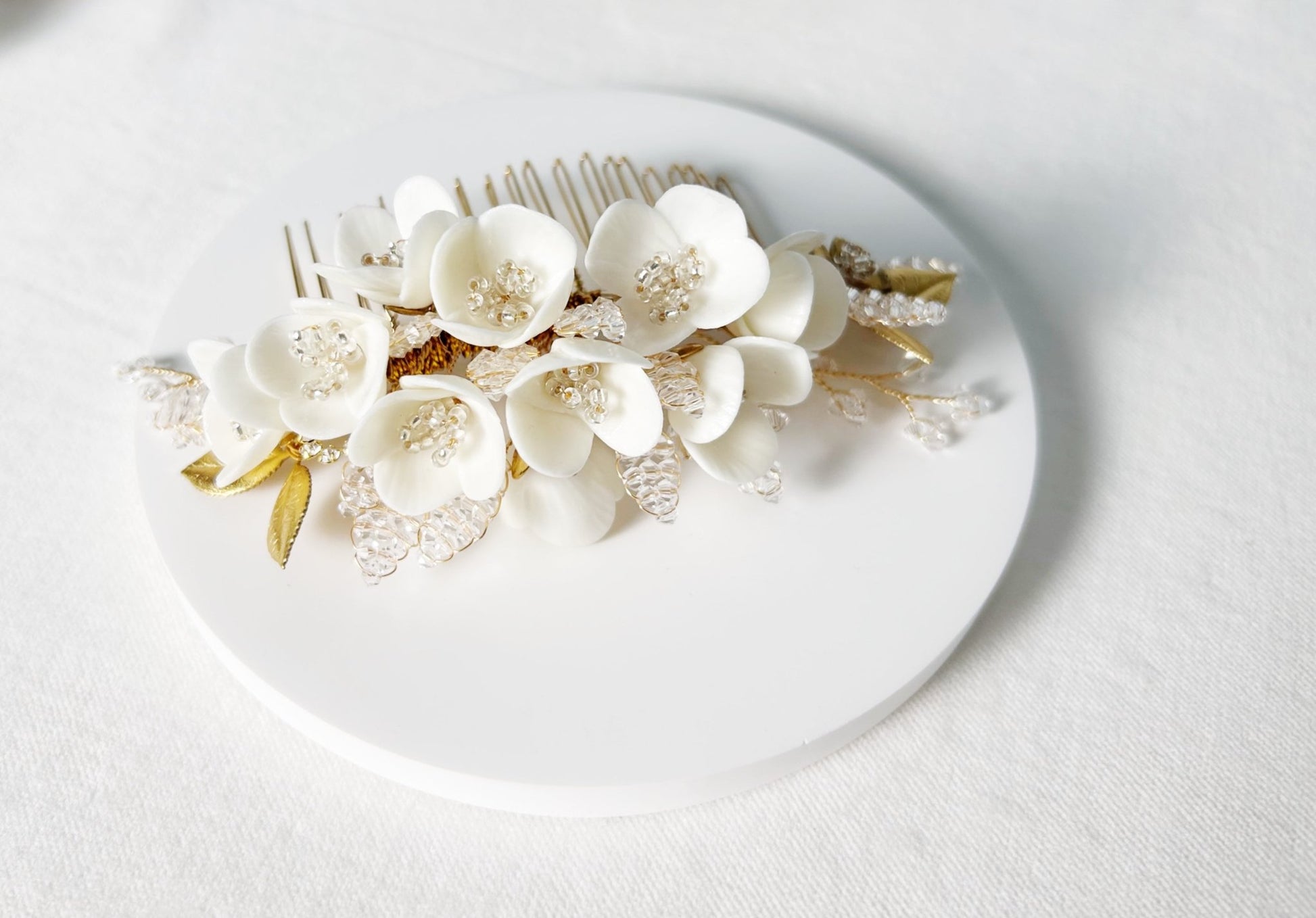 Floral hair comb with white flowers and gold accents on a white background