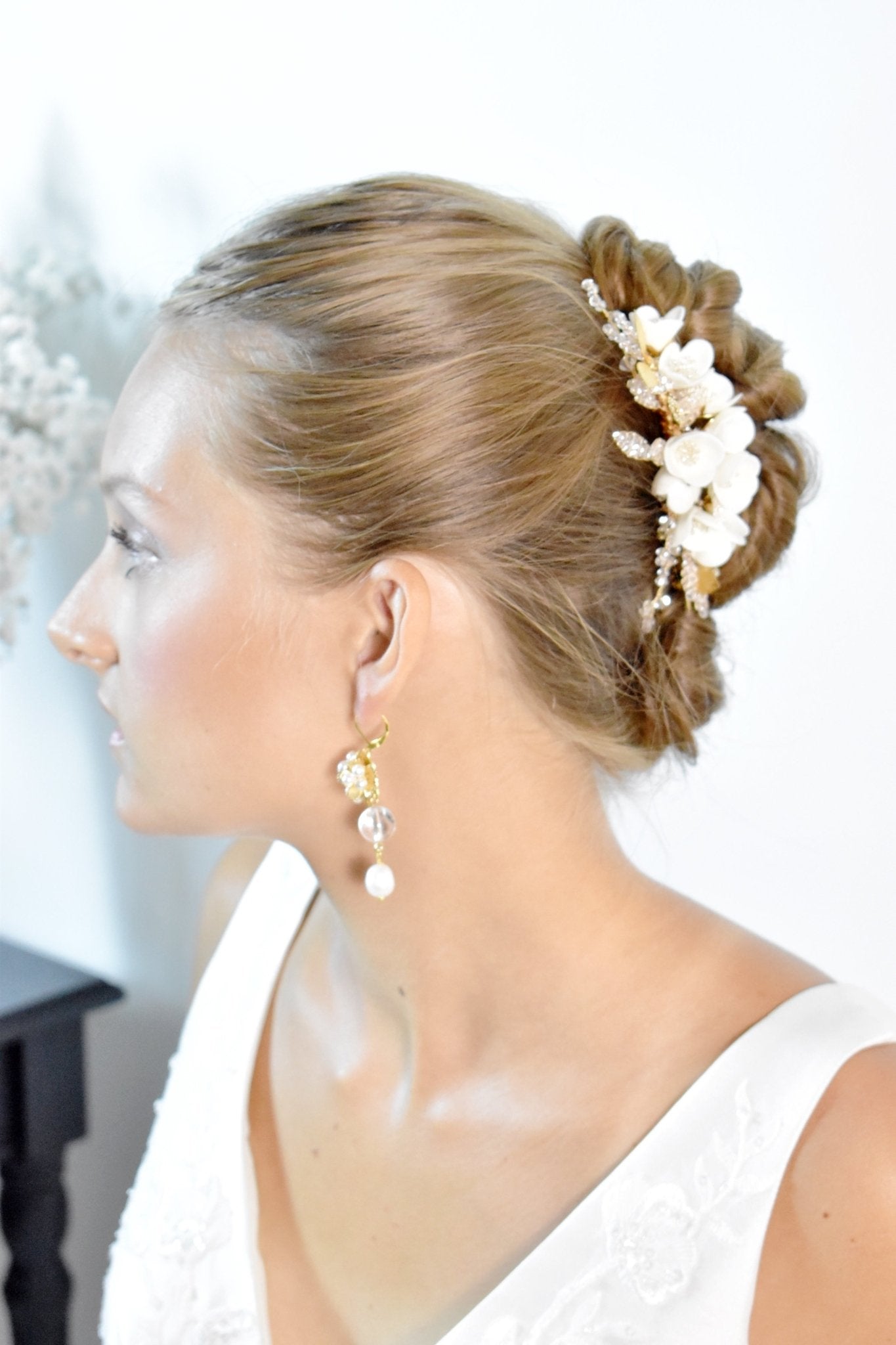 Woman with styled hair and floral hairpiece against a blurred background