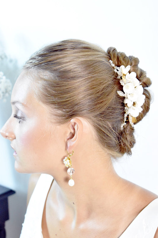 Woman with styled hair featuring flowers and earrings against a neutral background