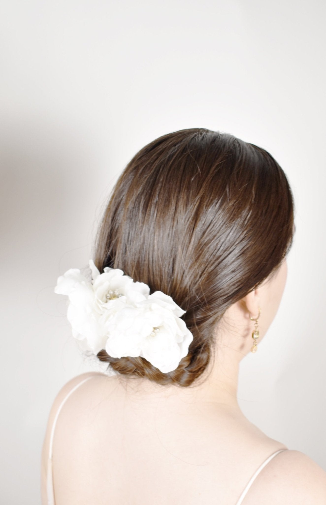 Woman with a white flower in her hair against a plain background