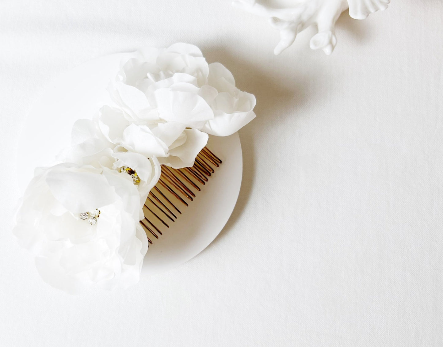 Wooden comb with white floral hair accessory on a light background