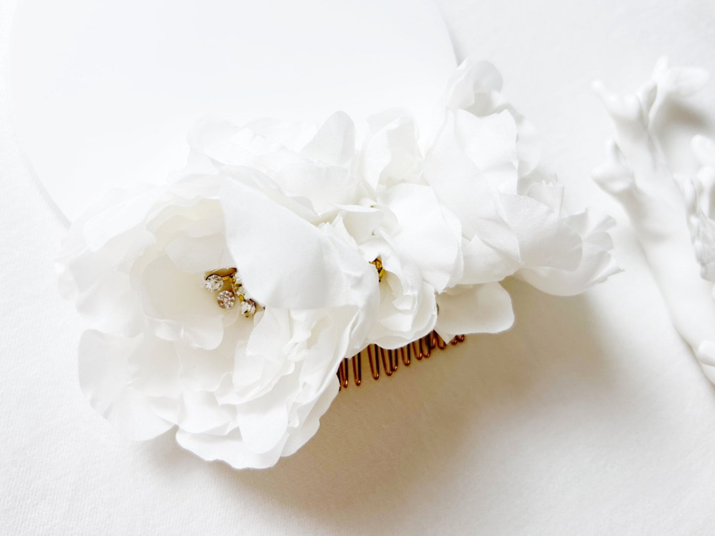 White floral headband with a gold comb on a white background