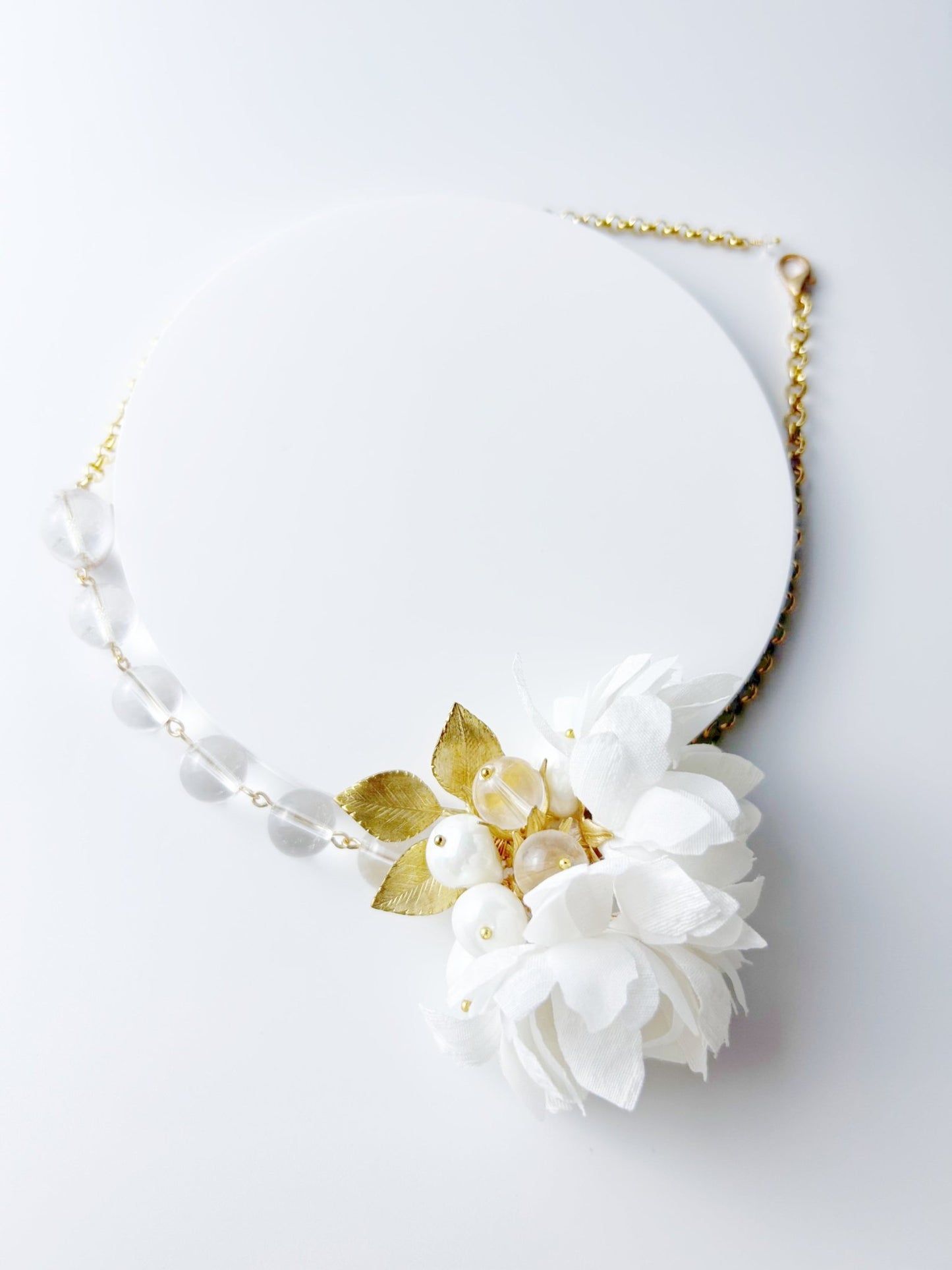 Necklace with white flowers and gold leaves on a light gray background