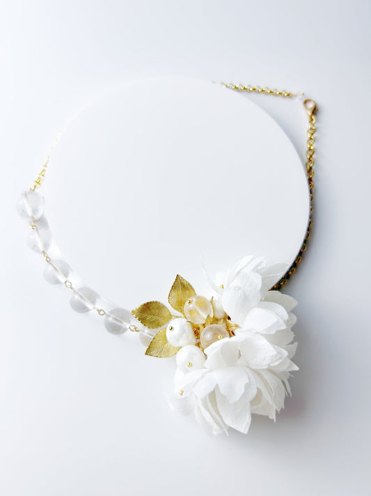 Necklace with white flowers and gold leaves on a light gray background