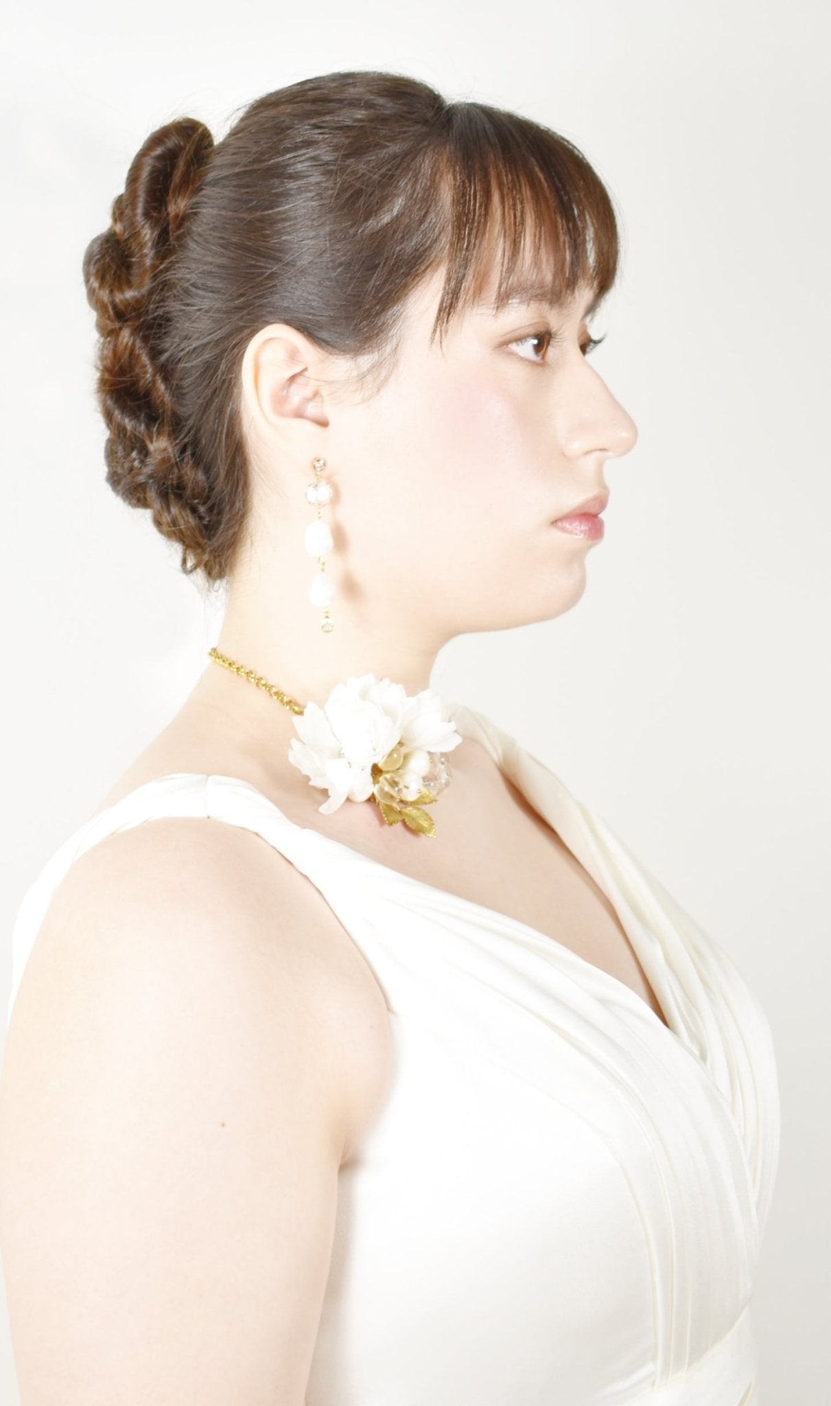 Woman in a white dress with a floral headpiece against a white background