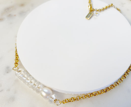 Gold chain necklace with pearls on a white dish