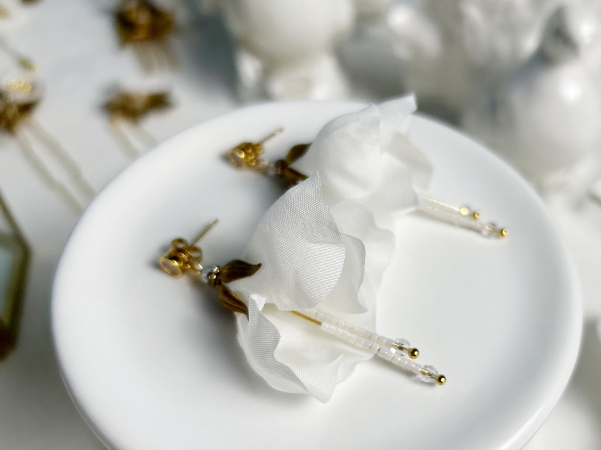 White earrings with gold accents on a white plate