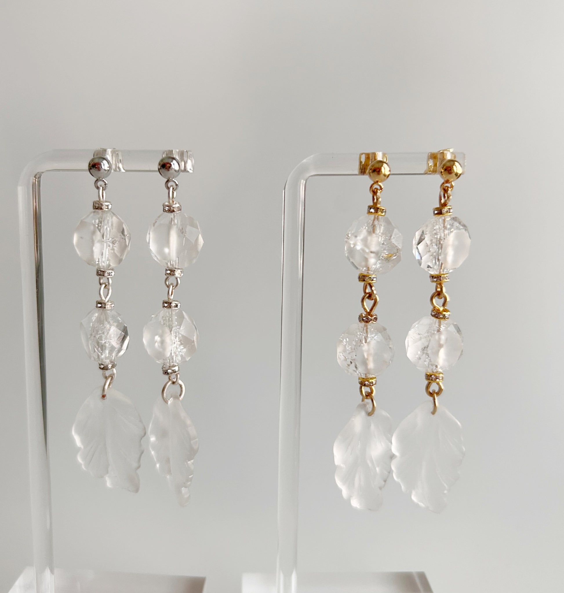 Pair of crystal drop earrings on clear stands against a white background
