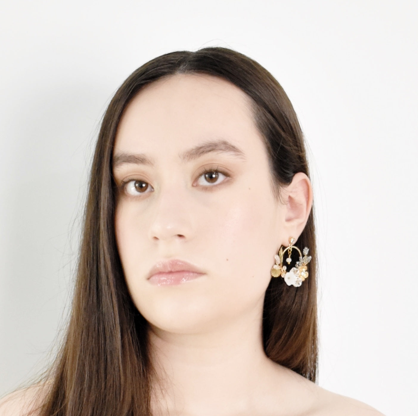 Woman wearing floral earrings against a plain background