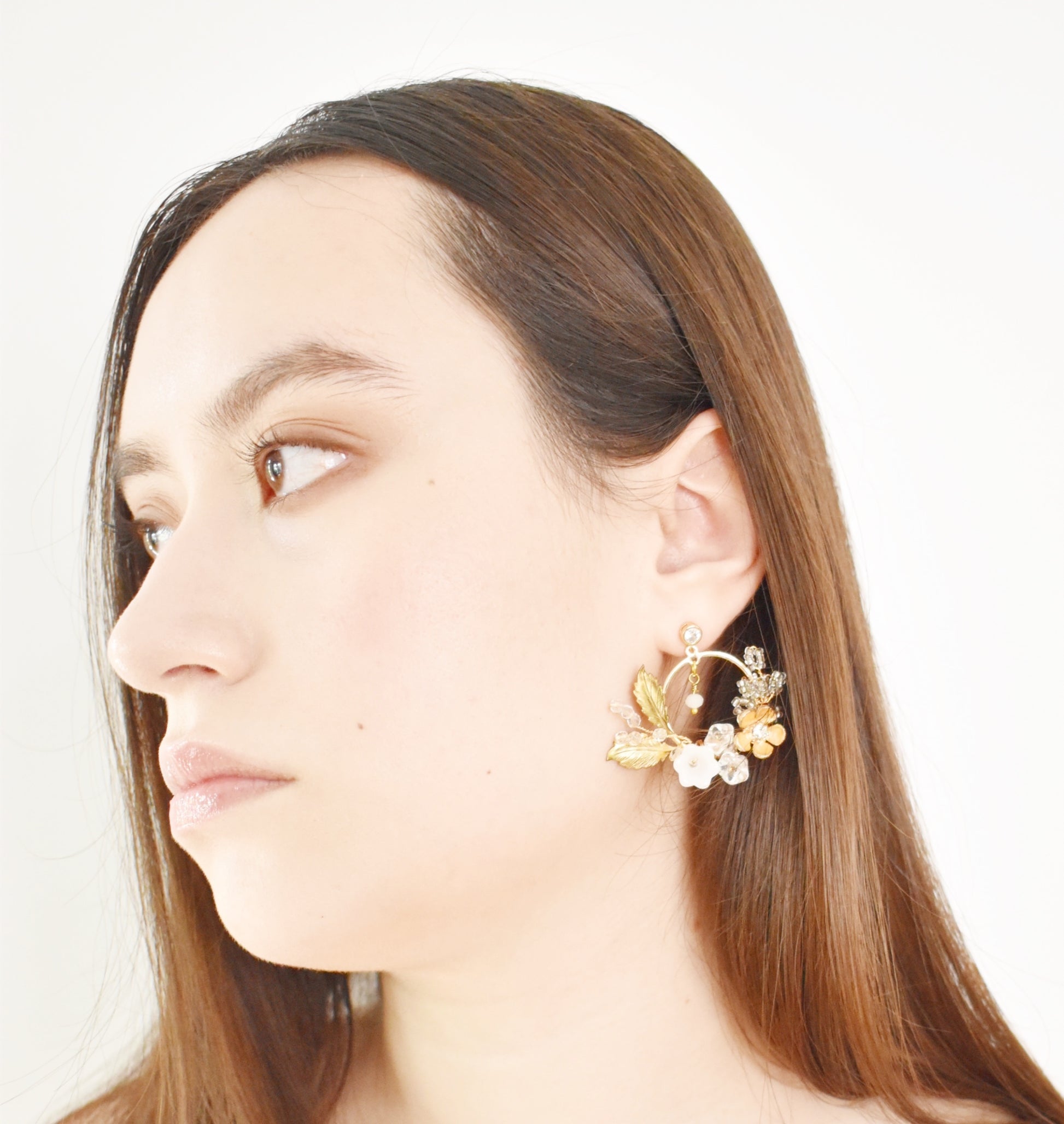 Close-up of a woman wearing floral hoop earrings on a white background