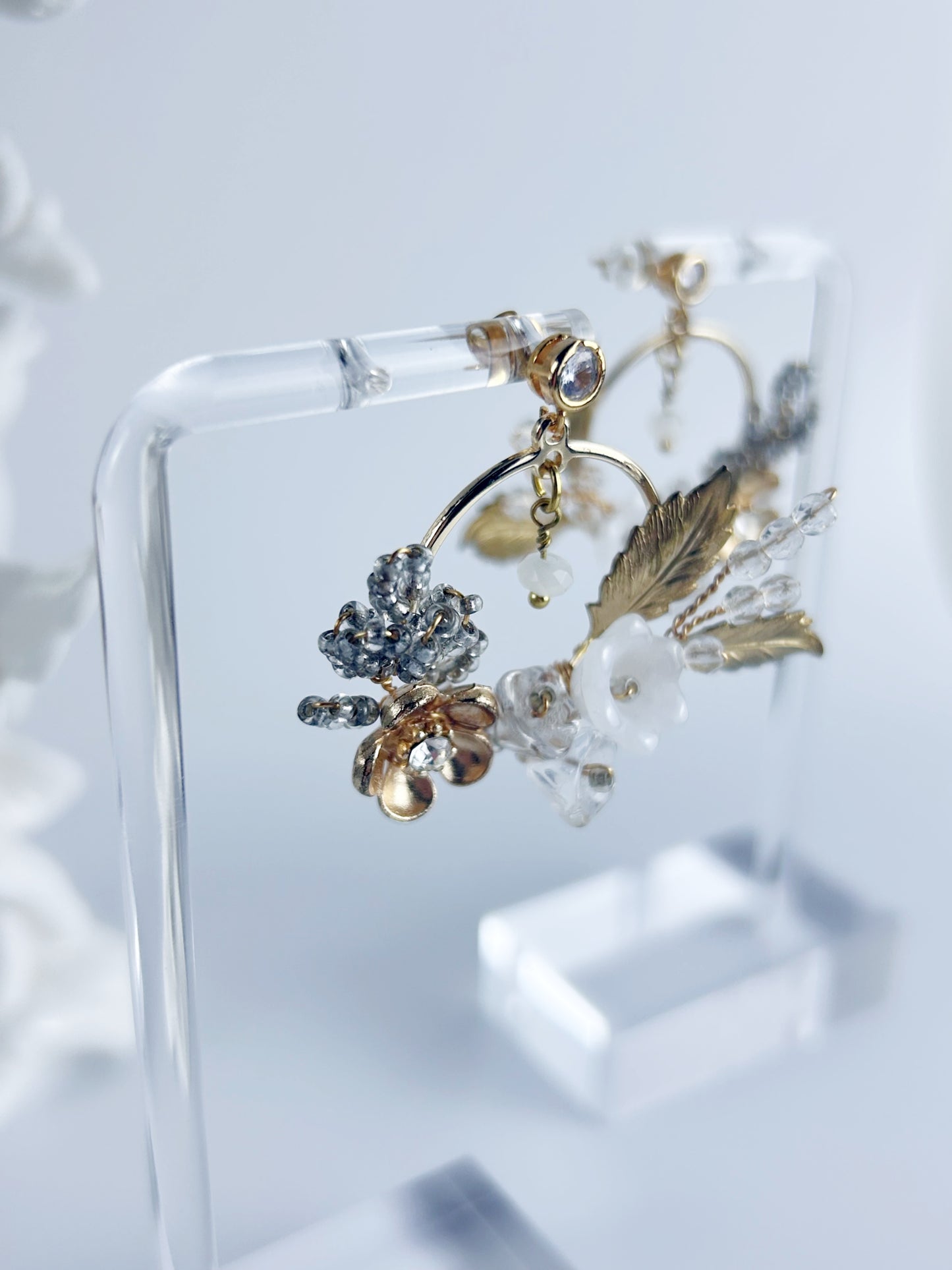 Pair of decorative earrings on a clear stand with a light background