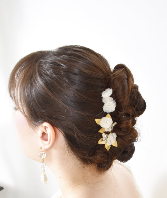 Woman with elegant hair styled in an updo with floral hair accessories on a white background