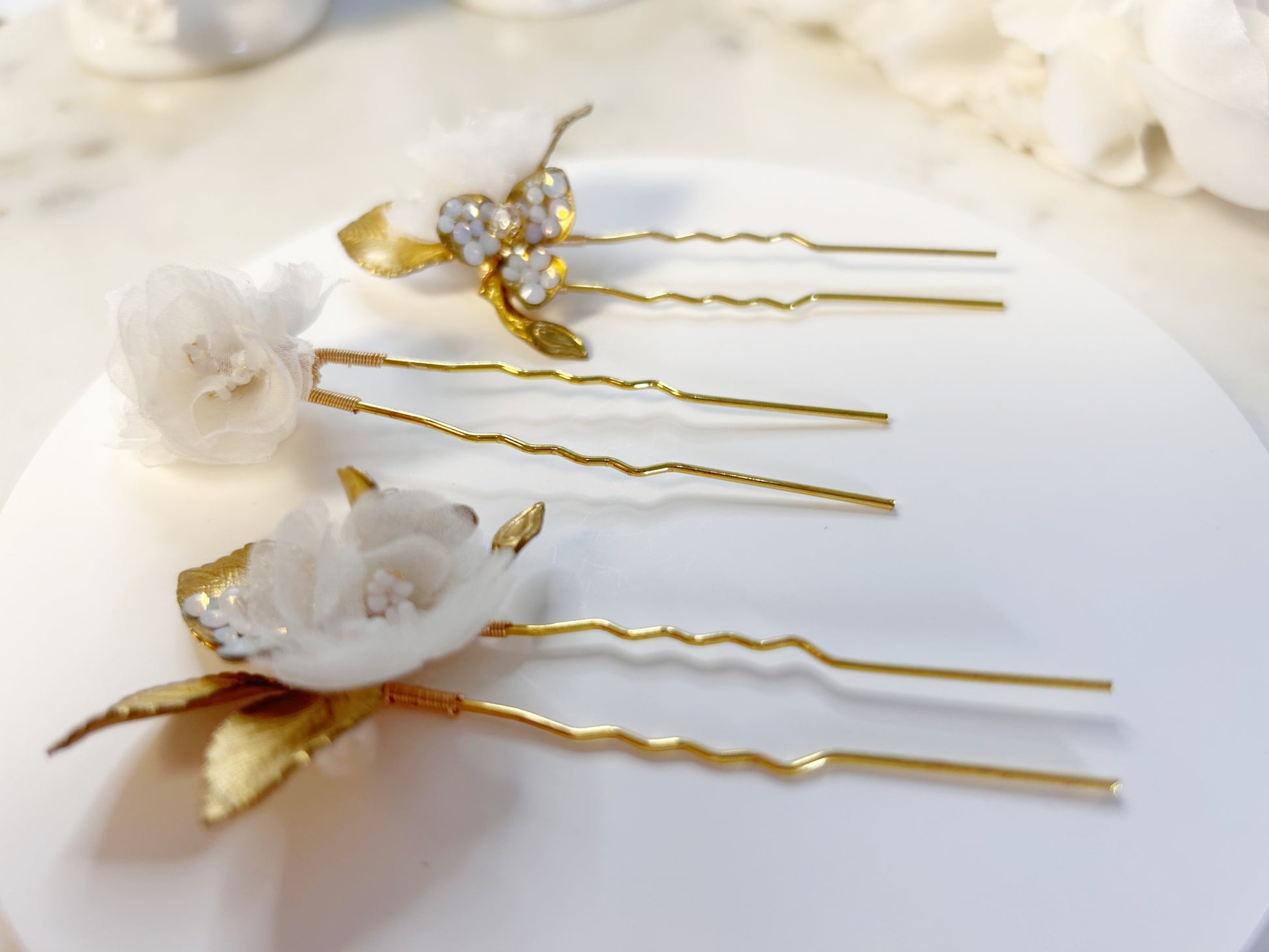 Decorative hair pins with floral designs on a white surface